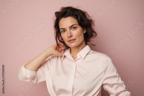 Portrait of a beautiful young woman in a pink shirt on a pink background
