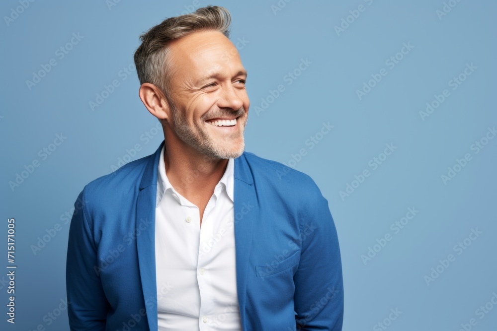 Handsome middle aged man laughing and looking away against blue background Handsome middle aged man laughing and looking away against blue background