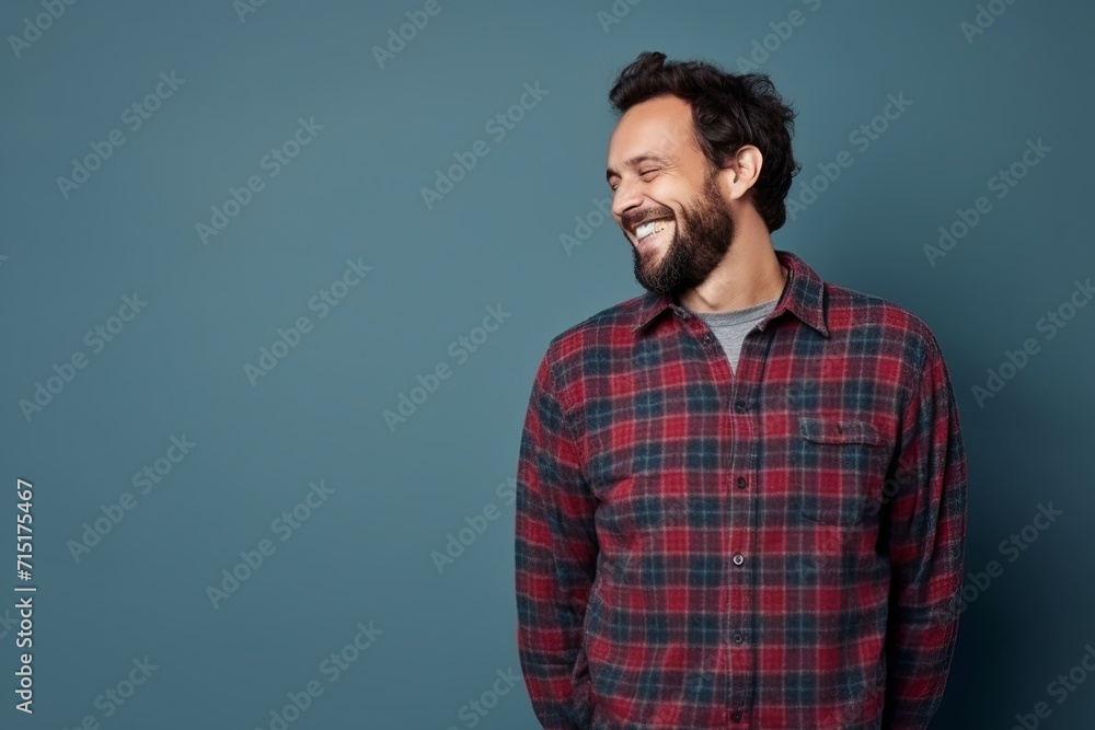 Portrait of a happy young man laughing at the camera while standing against blue background Portrait of a happy young man laughing at the camera while standing against blue background