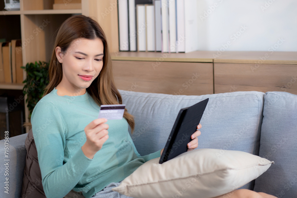 Young asian woman sitting on sofa using digital tablet shopping online with credit card buying to internet, female payment with business on couch, purchase and payment, business and lifestyles. Young asian woman sitting on sofa using digital tablet shopping online with credit card buying to internet, female payment with business on couch, purchase and payment, business and lifestyles.
