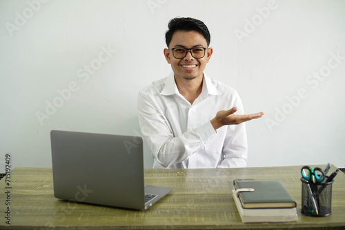 young asian businessman in a workplace presenting an idea while looking smiling towards, wear white shirt with glasses isolated