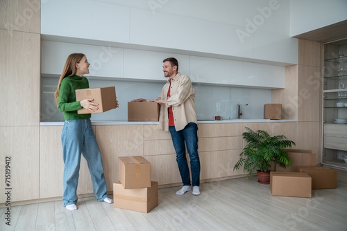 Merry smiling wife and cheerful happy husband holding packed cardbord boxes with belongnings. Joyful couple homeowners delighted with bying own flat, apartment, house. Relocation day to new property photo