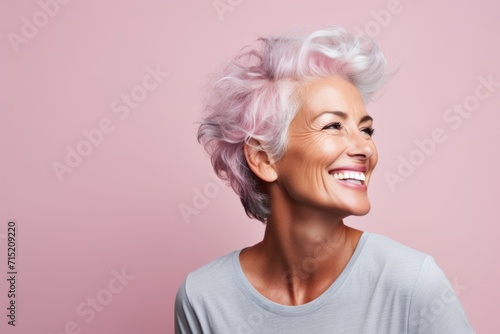 Portrait of smiling senior woman with pink hair on pink background.