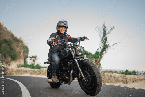 potrait of indonesian man on jacket and helmet riding motorbike outdoors