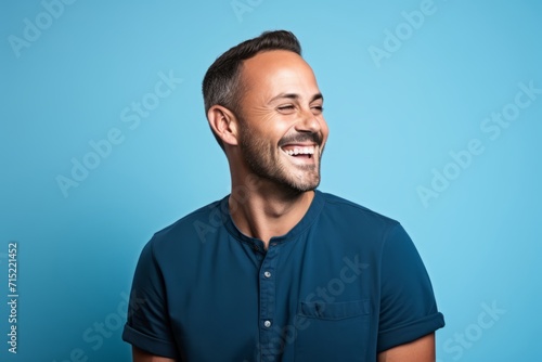 Portrait of a handsome young man laughing and looking away against blue background
