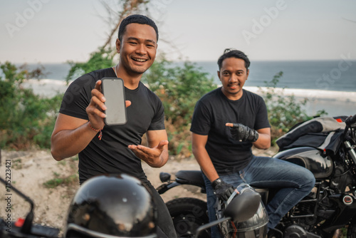 asian men sitting on motorcycle and holding mockup phone