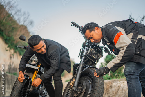 indonesian rider checking or inspecting motorbike wheel before traveling
