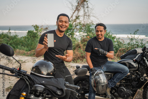 asian men sitting on motorbike and holding mockup phone © Odua Images