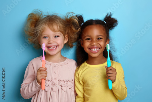 Portrait of two beautiful kids girls with perfect smile holding toothbrushes. Child dental care concept © Kien