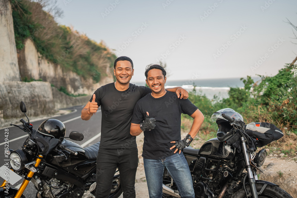 asian rider hugging friend while standing with thumb up gesture
