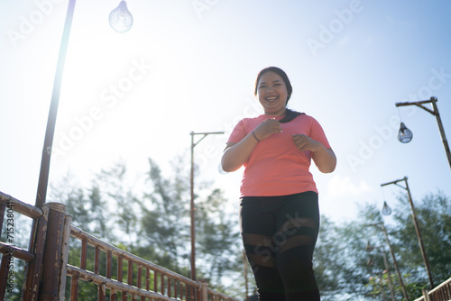 low angle view asian sporty woman jogging running around outdoor park © Odua Images