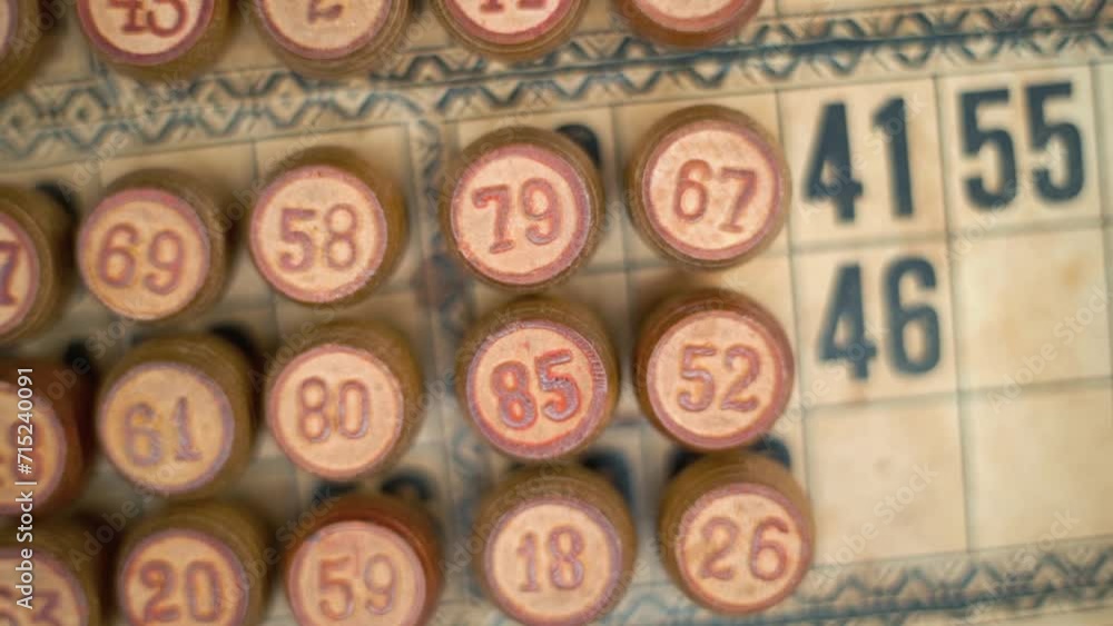 Cinematic close-up smooth pan left, shot from above of a Bingo wooden barrels, woody figures, old numbers background, vintage board game, lucky number, professional lighting, slow motion 120 fps Cinematic close-up smooth pan left, shot from above of a Bingo wooden barrels, woody figures, old numbers background, vintage board game, lucky number, professional lighting, slow motion 120 fps
