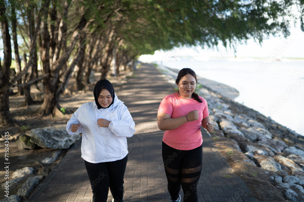 Fototapeta premium asian women in sportswear running around lakeside together