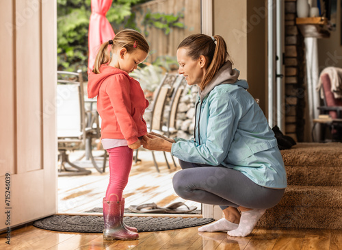 Quadro su tela Mother getting her child dressed up in warm jacket getting ready morning routine