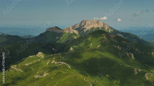 Green mountain hills. Two majestic mountains with sheer cliffs rise in the background. These are Maly and Bolshoi Tkhach mountains. View from the air. Summer camping in the Caucasus Mountains. photo