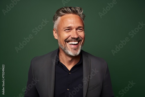 Portrait of a happy senior man laughing against green chalkboard background