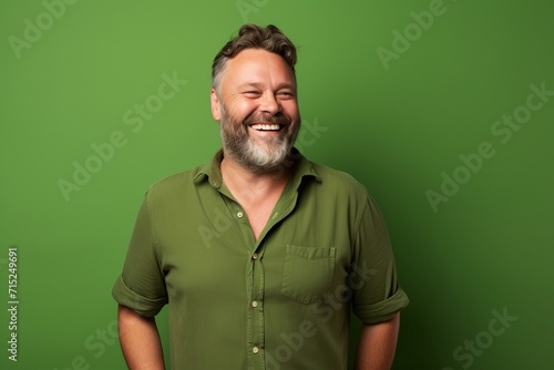 Portrait of a happy middle-aged man laughing against a green background