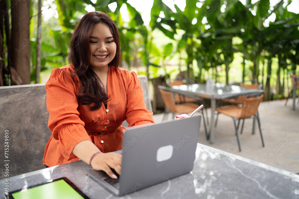 plus size woman working in outdoor cafe using laptop and tablet plus size woman working in outdoor cafe using laptop and tablet