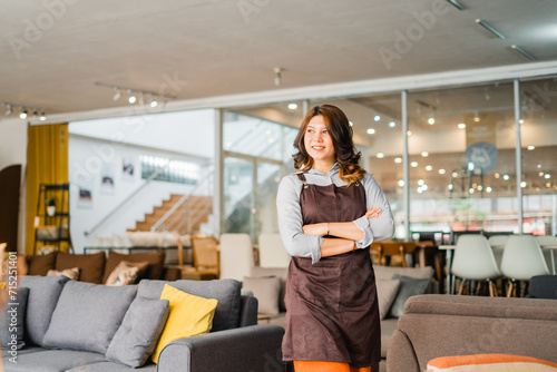 attractive woman in apron with crossed arms standing in front of couch in furniture store department