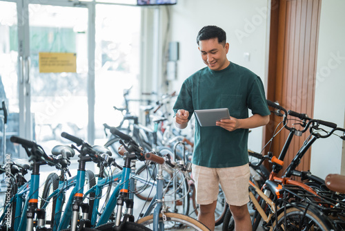 young man checks out a new bike while using a tablet at a bike shop