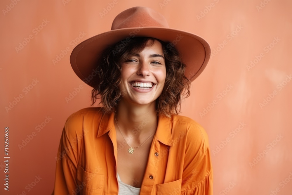 Portrait of a beautiful young woman in orange shirt and hat smiling