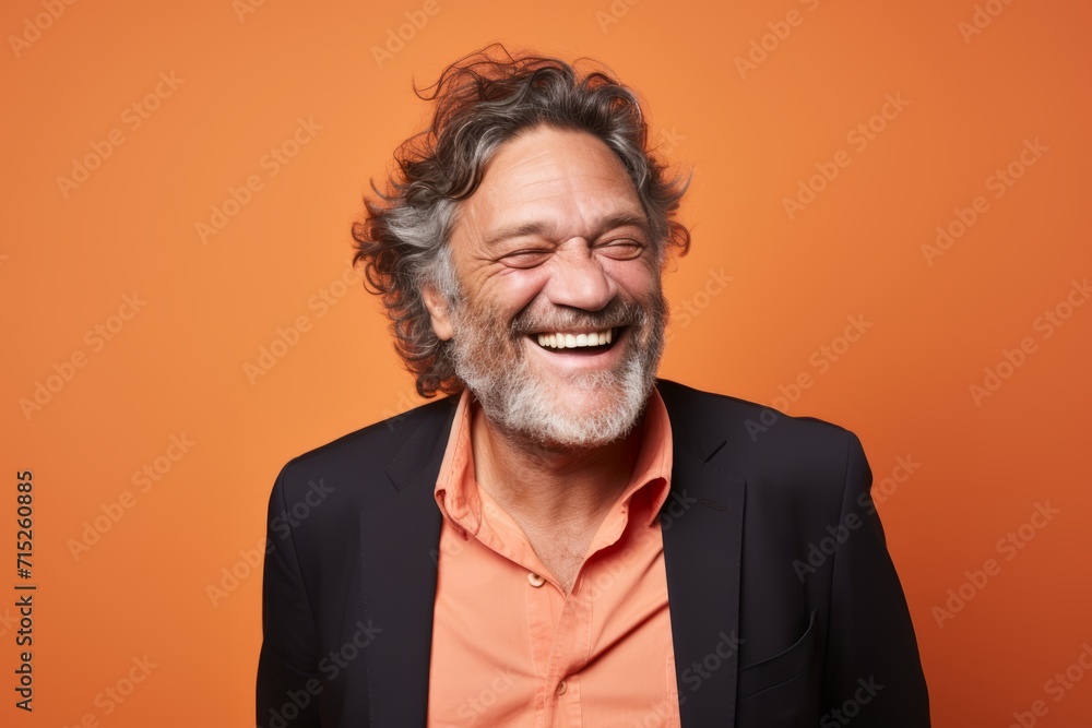 Cheerful senior man laughing and looking at camera over orange background Cheerful senior man laughing and looking at camera over orange background