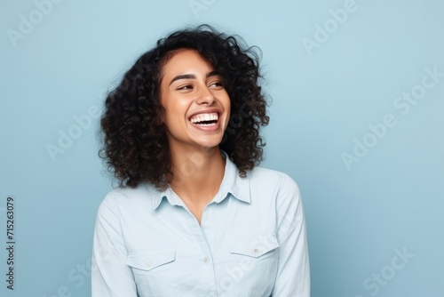 Portrait of happy young african american woman laughing against blue background