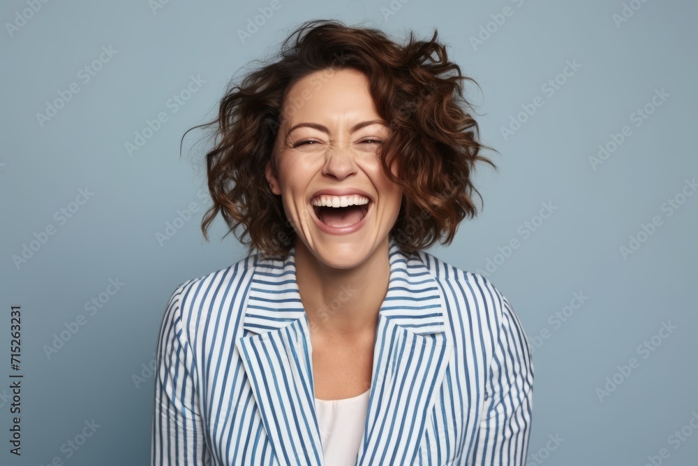 Portrait of a happy young woman laughing and looking at camera over blue background Portrait of a happy young woman laughing and looking at camera over blue background