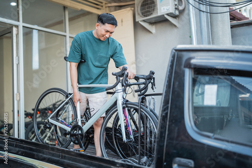man removing bicycle from pickup car at a bike shop background