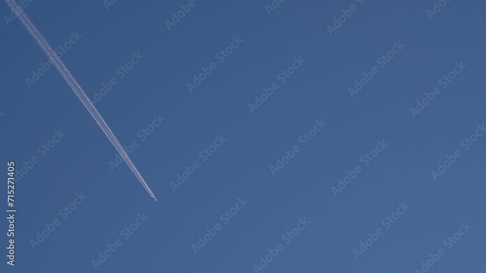 Airplane flying at high altitude with contrails against clear blue sky Airplane flying at high altitude with contrails against clear blue sky