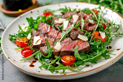 Closeup view of Beef tagliata with arugula, cherry tomatoes, Grana Padano cheese shavings, and balsamic glaze