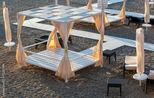 Empty sunbeds on a pebble beach at sunset photo