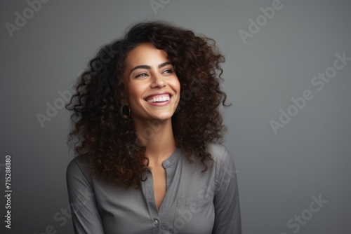 Portrait of a happy young businesswoman with curly hair against grey background