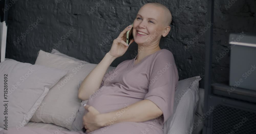 Carefree pregnant woman speaking on mobile phone laughing relaxing in bed in cozy bedroom. Cellphone communication and pregnancy concept. Carefree pregnant woman speaking on mobile phone laughing relaxing in bed in cozy bedroom. Cellphone communication and pregnancy concept.