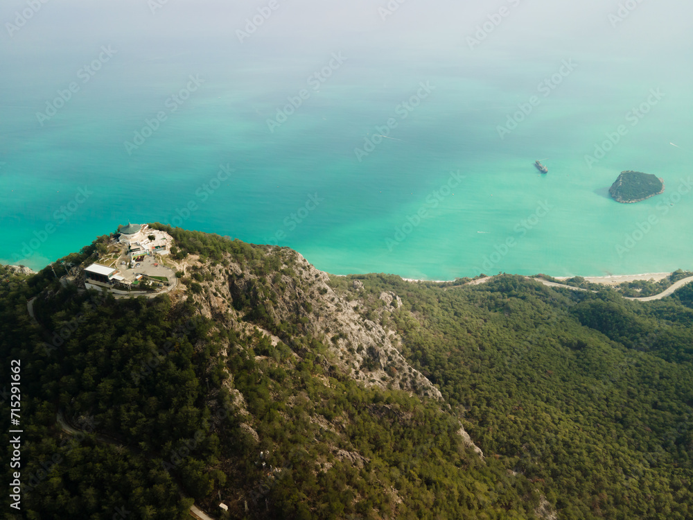 Beautiful landscape, natural background from a bird's-eye view, photo from a drone. High mountains with dense green forest on the background of a clear turquoise sea. Copy space, mockup.