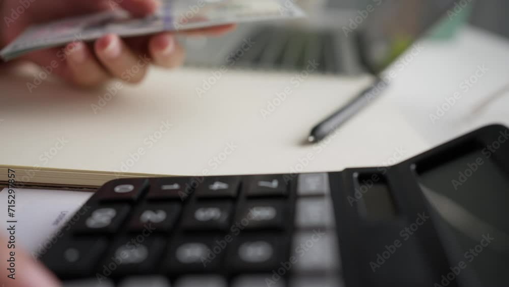 Close up woman sits at table, home office in front of laptop and note book and holds dollar bills in hands, counts money. Budget planning. Revenue, profit, wealth. Close up woman sits at table, home office in front of laptop and note book and holds dollar bills in hands, counts money. Budget planning. Revenue, profit, wealth.