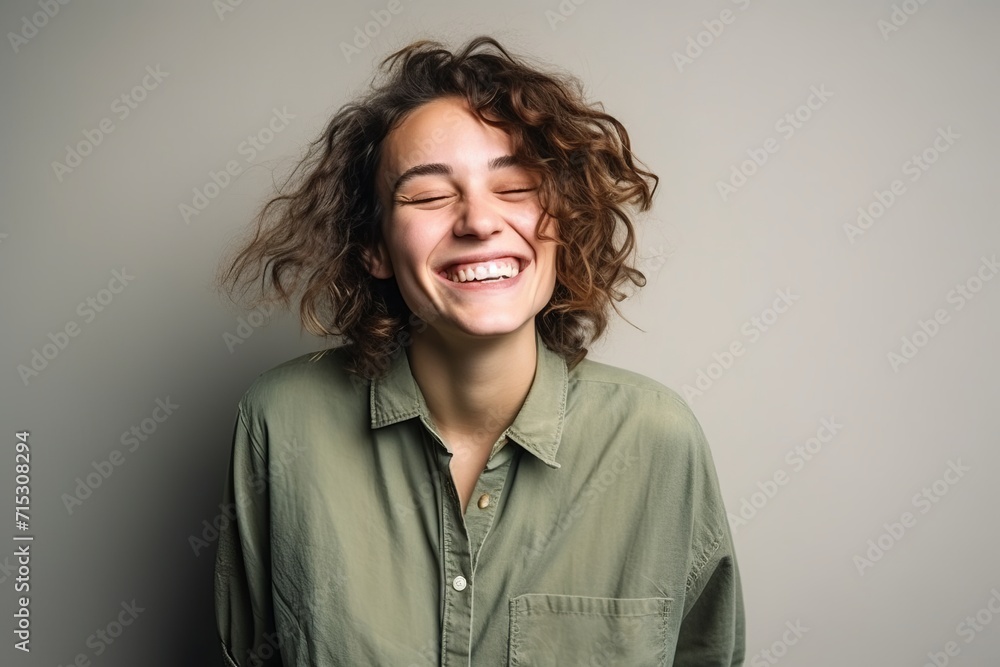 Portrait of a happy young woman laughing with closed eyes on grey background Portrait of a happy young woman laughing with closed eyes on grey background