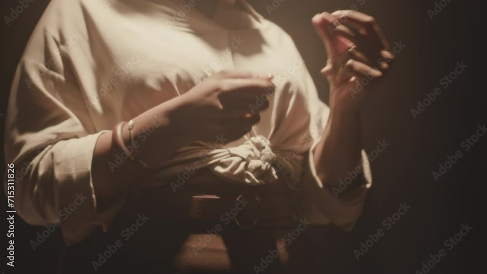 Cropped shot of vibrant African American female singer snapping her fingers before start singing under yellow projector light on dark smoky stage