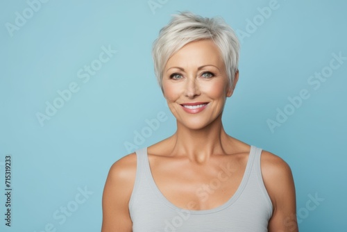 Portrait of beautiful middle aged woman smiling at camera. Blue background.