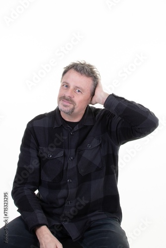 Happy bearded handsome man with hand in hair standing over white background