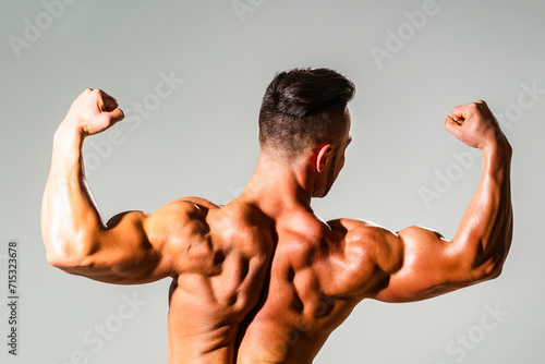 Strong Sexy Athletic Man. Fitness Model showing naked Back. Man Power. Perfect Shoulders and Back Muscles. Muscular Man showing Strength, Back view. Sexy body. Strong Power Shoulders.