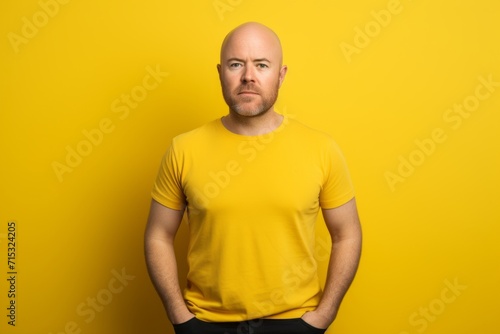 Portrait of a bald man in a yellow T-shirt on a yellow background