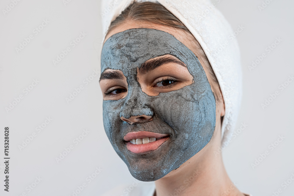 Attractive lady wear white towel applying black clay mask on her face isolated on white Attractive lady wear white towel applying black clay mask on her face isolated on white