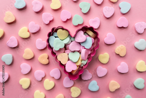 flat lay of a pile of candy hearts against a pink background