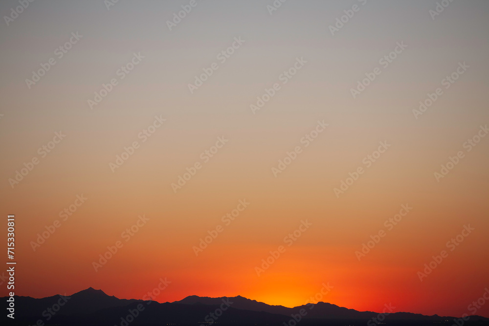 Red-orange sky after sunset silhouetted mountains below