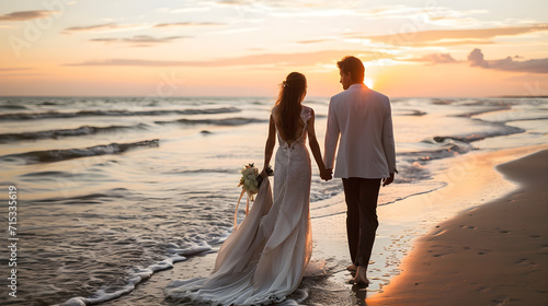 The bride and groom walk along the ocean in wedding clothes at sunset