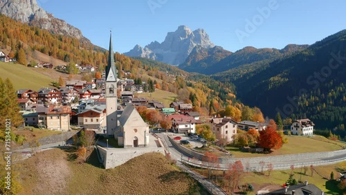 4k drone flight moving to the side footage (Ultra High Definition) of San Lorenzo Catholic church. Exciting autumn cityscape of Selva di Cadore village, Province of Belluno, Italy, Europe. photo