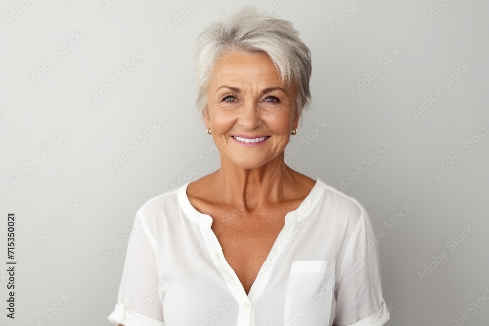 Closeup portrait of a happy senior woman looking at camera over grey background Closeup portrait of a happy senior woman looking at camera over grey background