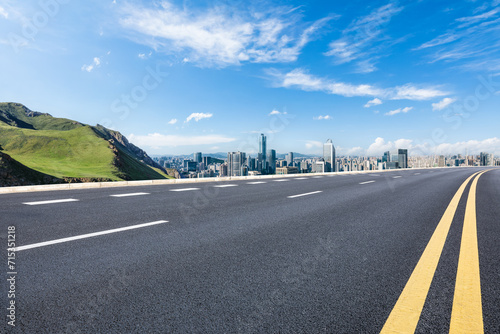 Asphalt road and green mountain with city skyline landscape under blue sky. high angle view. photo