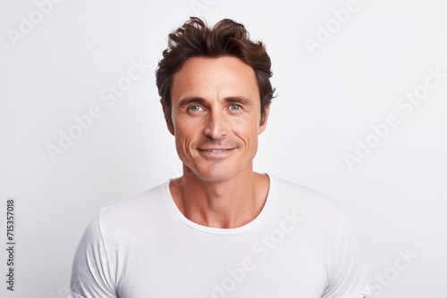 Portrait of handsome mature man looking at camera and smiling while standing against grey background © Loli